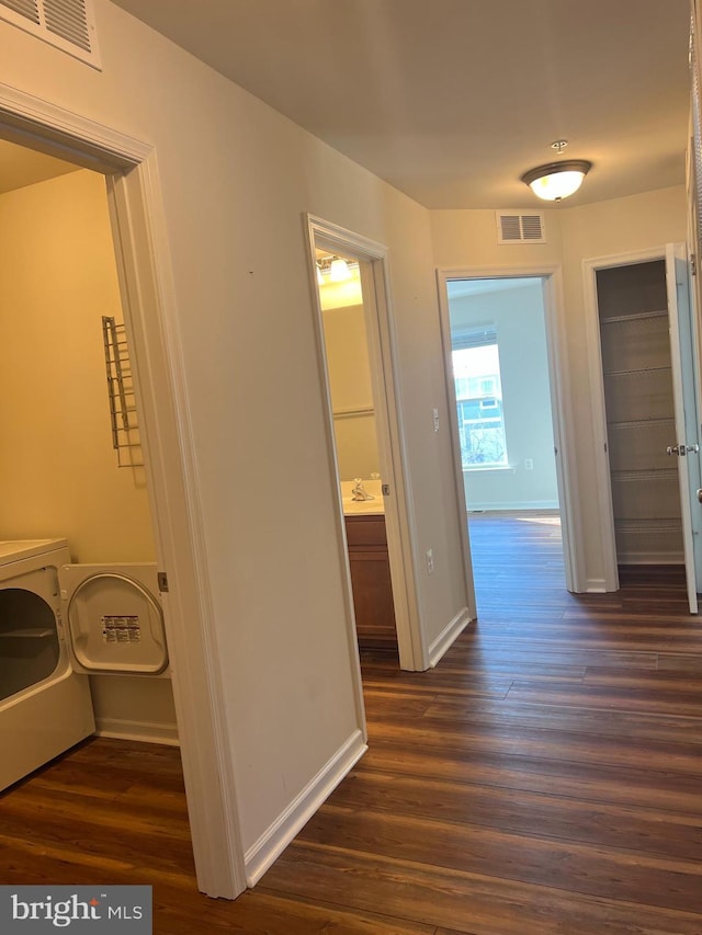 hall with sink, separate washer and dryer, and dark wood-type flooring