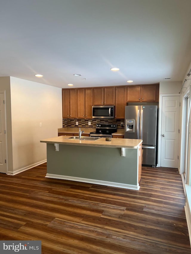 kitchen with appliances with stainless steel finishes, a kitchen island with sink, and dark hardwood / wood-style floors