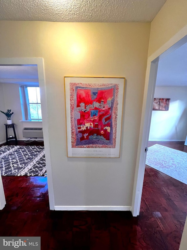 interior details featuring hardwood / wood-style flooring, a wall mounted AC, and a textured ceiling