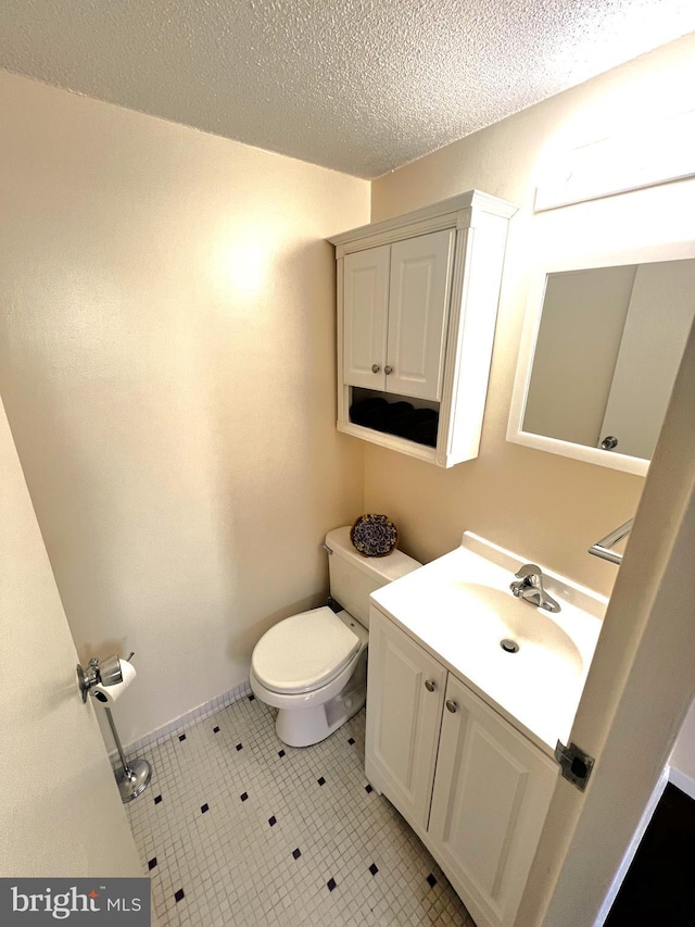 bathroom with vanity, a textured ceiling, and toilet