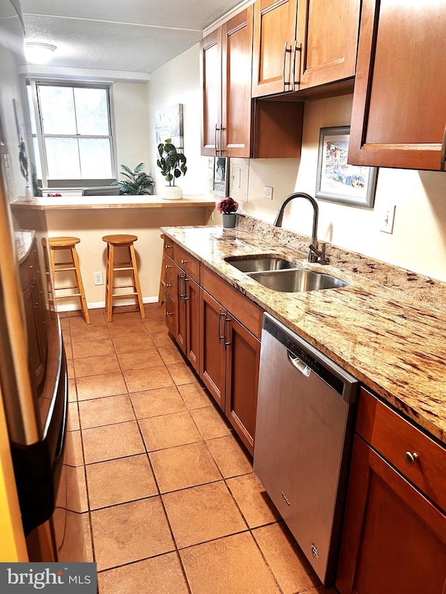 kitchen with dishwasher, sink, light tile patterned floors, and light stone counters