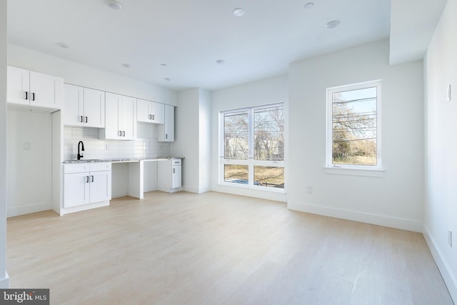 kitchen featuring sink, white cabinetry, light wood-type flooring, and tasteful backsplash