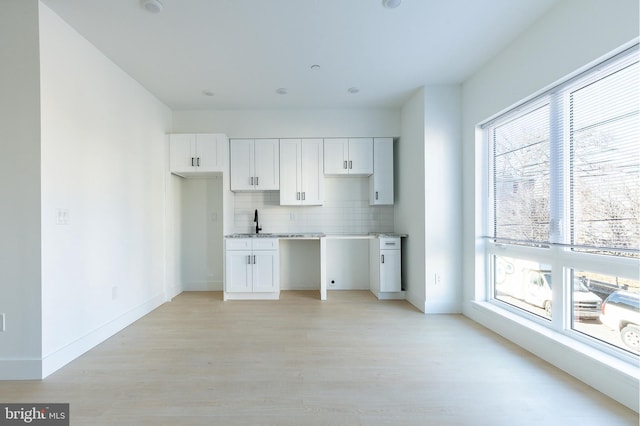 kitchen with decorative backsplash, white cabinetry, and a wealth of natural light