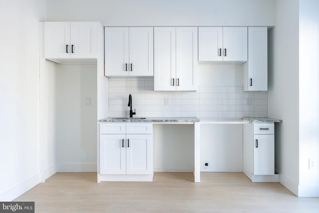 kitchen featuring sink, backsplash, and white cabinetry