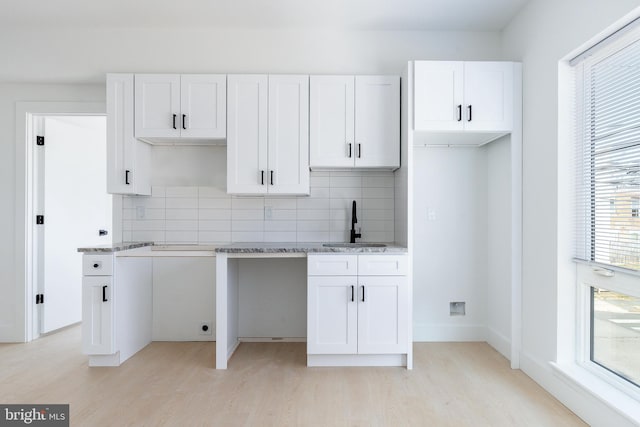 kitchen featuring sink, decorative backsplash, white cabinetry, and light wood-type flooring