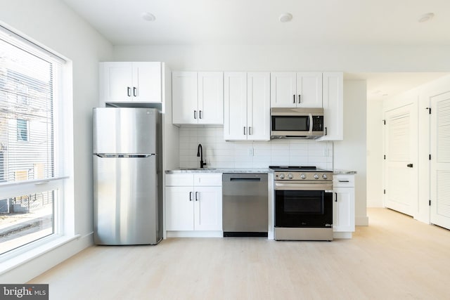 kitchen featuring sink, stainless steel appliances, white cabinetry, and decorative backsplash