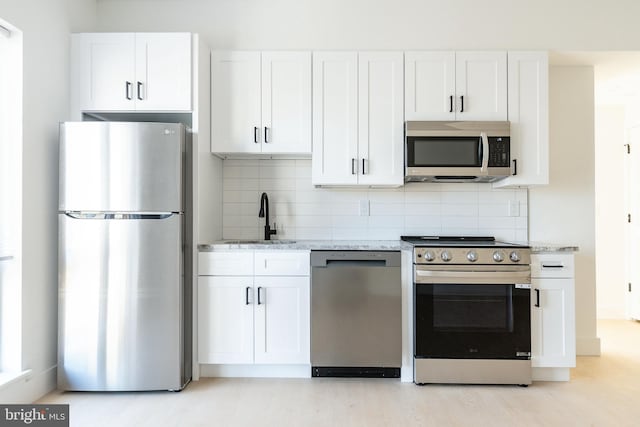 kitchen with appliances with stainless steel finishes, white cabinetry, and sink