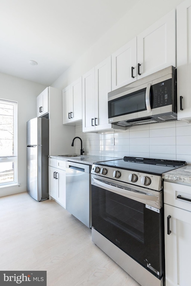 kitchen featuring sink, white cabinets, tasteful backsplash, and appliances with stainless steel finishes