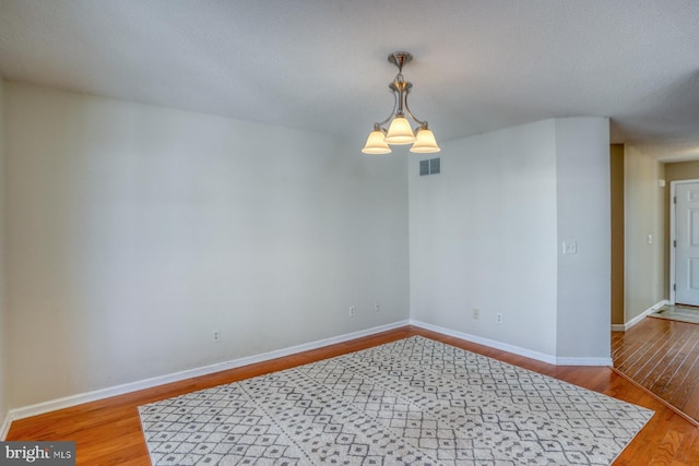 spare room with a notable chandelier and hardwood / wood-style flooring