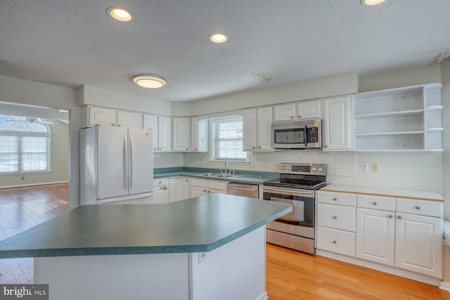 kitchen featuring white cabinetry, appliances with stainless steel finishes, a textured ceiling, light hardwood / wood-style flooring, and sink