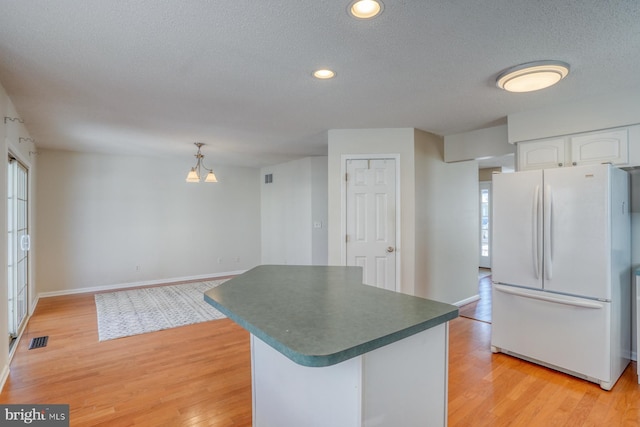 kitchen with decorative light fixtures, light hardwood / wood-style floors, white cabinets, and white fridge