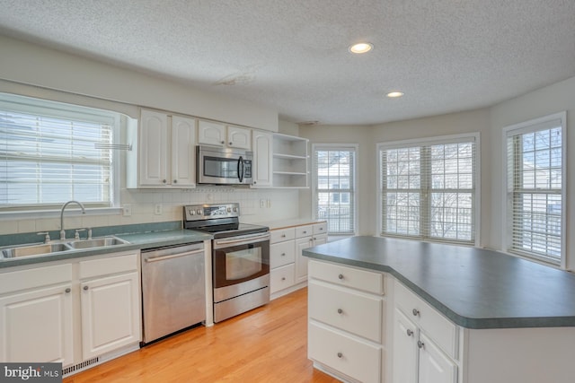 kitchen with appliances with stainless steel finishes, sink, a textured ceiling, white cabinetry, and tasteful backsplash