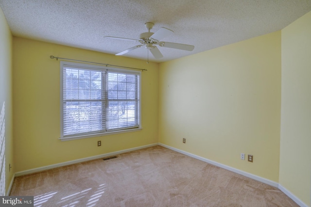 spare room with a textured ceiling, light carpet, and ceiling fan