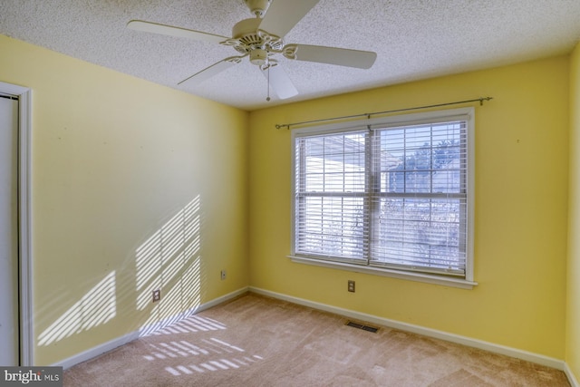 carpeted empty room with ceiling fan and a textured ceiling