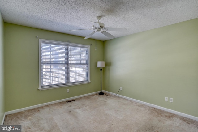 spare room featuring ceiling fan, light carpet, and a textured ceiling