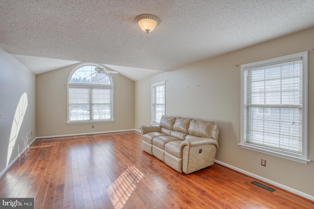 living room with wood-type flooring, a textured ceiling, ceiling fan, and vaulted ceiling