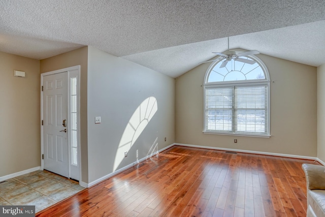 entrance foyer featuring lofted ceiling, a textured ceiling, ceiling fan, and light hardwood / wood-style flooring