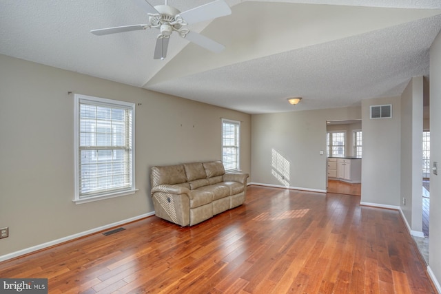 unfurnished room featuring hardwood / wood-style flooring, a textured ceiling, ceiling fan, and vaulted ceiling