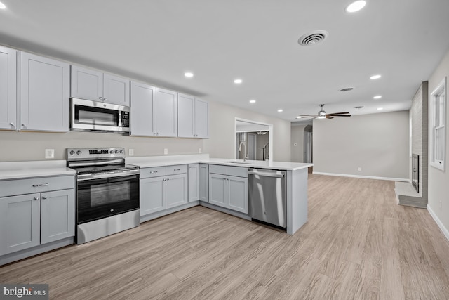 kitchen with kitchen peninsula, light hardwood / wood-style flooring, stainless steel appliances, ceiling fan, and sink