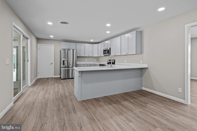 kitchen featuring white cabinetry, light wood-type flooring, kitchen peninsula, and appliances with stainless steel finishes