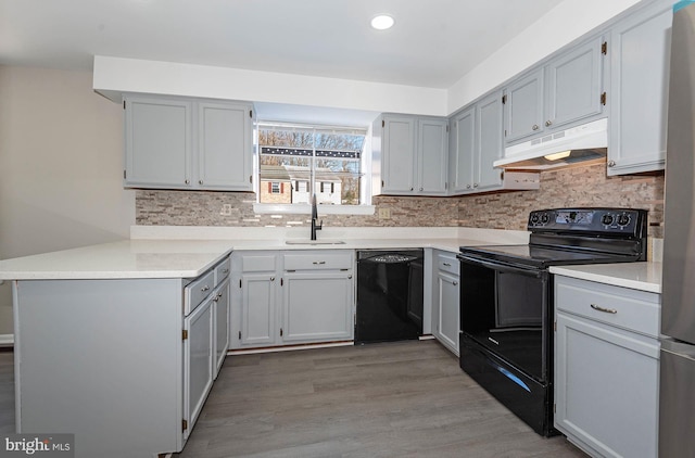 kitchen with sink, hardwood / wood-style flooring, kitchen peninsula, black appliances, and gray cabinetry