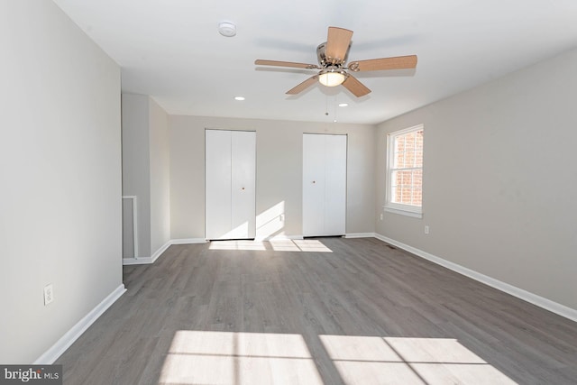 unfurnished bedroom featuring ceiling fan, light hardwood / wood-style floors, and multiple closets