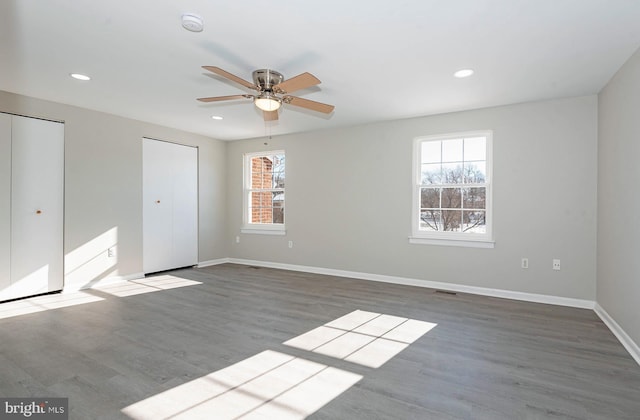 unfurnished bedroom with multiple windows, two closets, ceiling fan, and light hardwood / wood-style floors