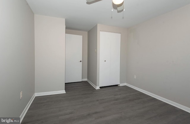 unfurnished bedroom featuring a closet, ceiling fan, and dark wood-type flooring