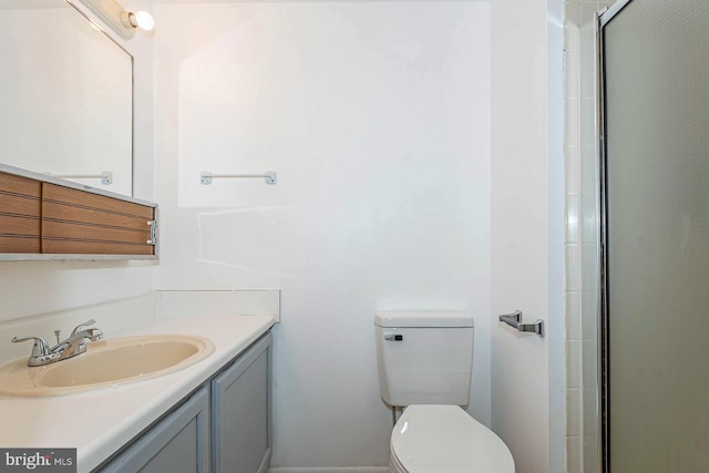 bathroom featuring toilet, vanity, and a shower with shower door