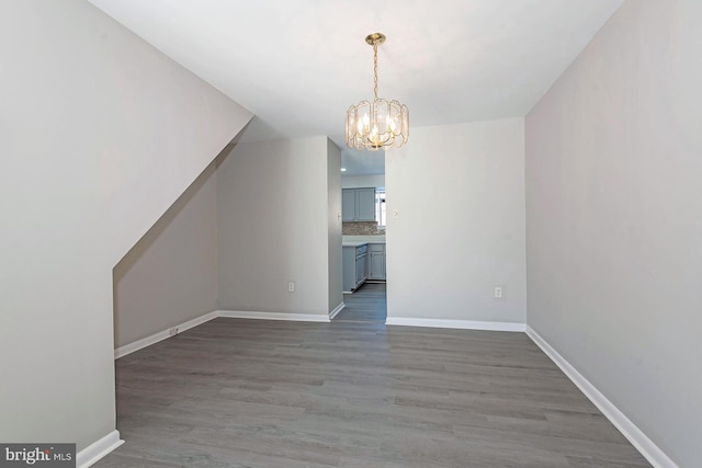 unfurnished dining area with a notable chandelier and dark hardwood / wood-style flooring