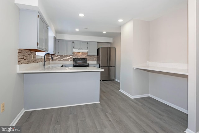 kitchen featuring sink, kitchen peninsula, stainless steel refrigerator, gray cabinets, and black range with electric cooktop