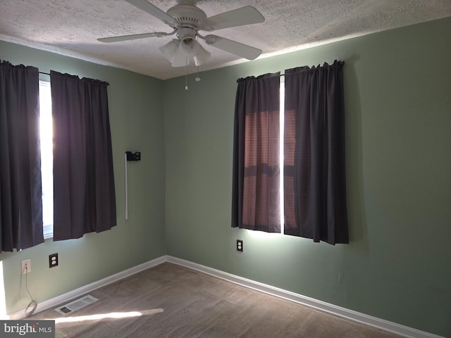 empty room featuring ceiling fan, carpet, and a textured ceiling