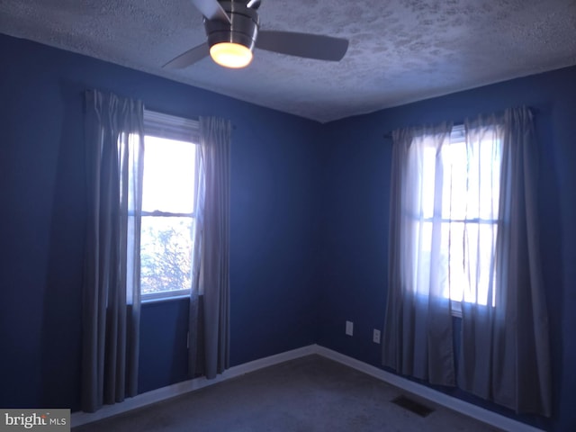 empty room featuring a textured ceiling, ceiling fan, and carpet floors