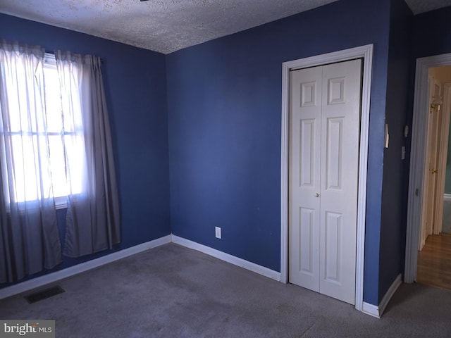 unfurnished bedroom featuring a textured ceiling, a closet, and carpet flooring