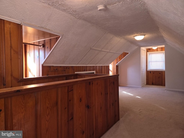 bonus room with lofted ceiling, light colored carpet, and a textured ceiling