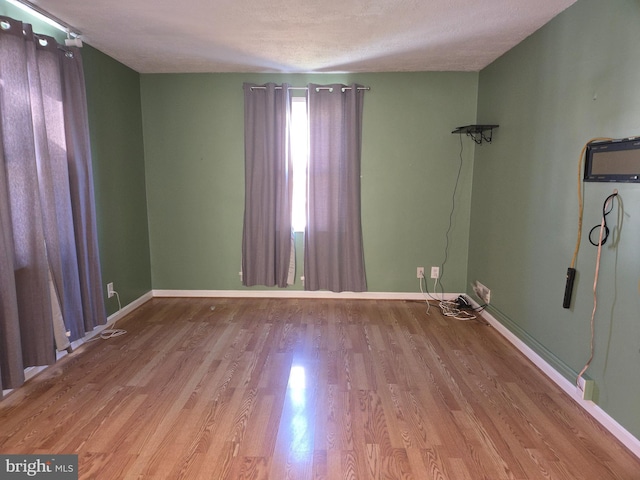 spare room with light hardwood / wood-style floors and a textured ceiling