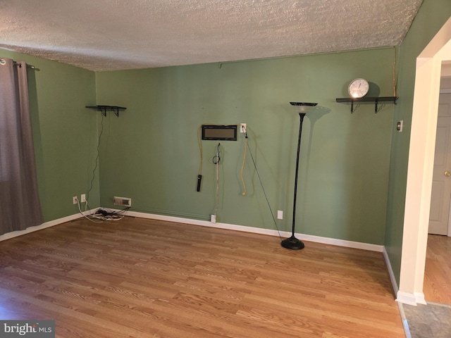 spare room featuring a textured ceiling and hardwood / wood-style flooring