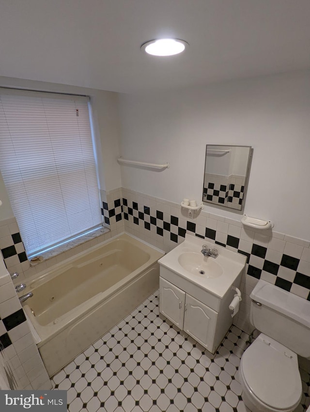 bathroom with a bathtub, vanity, tile walls, and toilet