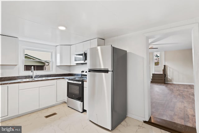 kitchen featuring white cabinetry, ceiling fan, appliances with stainless steel finishes, and sink