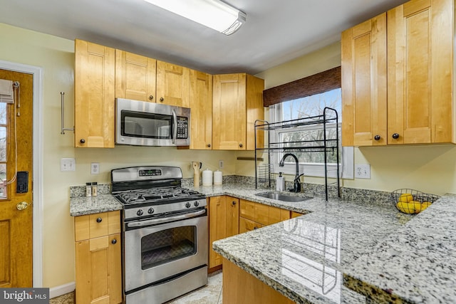 kitchen with light stone counters, stainless steel appliances, and sink