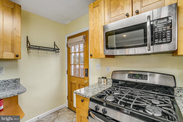 kitchen with light tile patterned flooring, light stone countertops, and appliances with stainless steel finishes