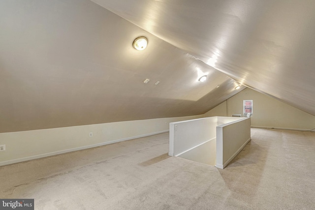 additional living space featuring lofted ceiling and light colored carpet