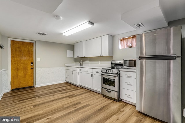 kitchen featuring white cabinetry, appliances with stainless steel finishes, sink, and light wood-type flooring