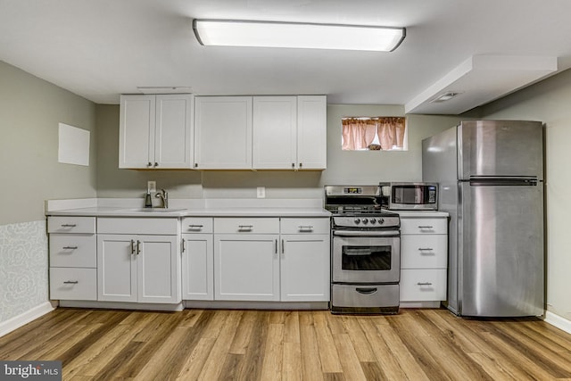 kitchen with light hardwood / wood-style floors, white cabinets, and appliances with stainless steel finishes