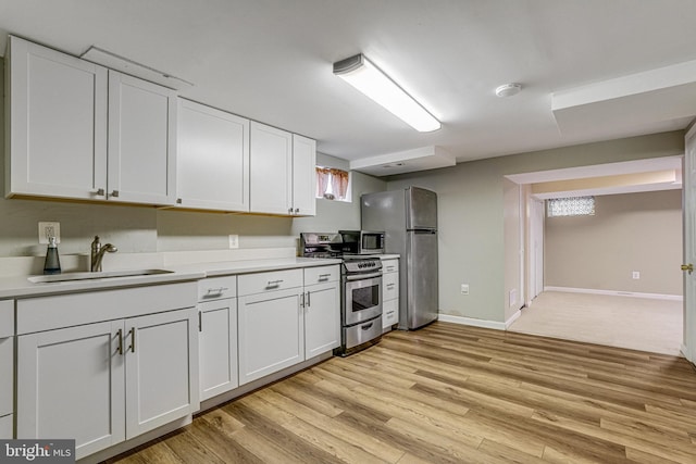 kitchen featuring appliances with stainless steel finishes, light hardwood / wood-style floors, sink, and white cabinets