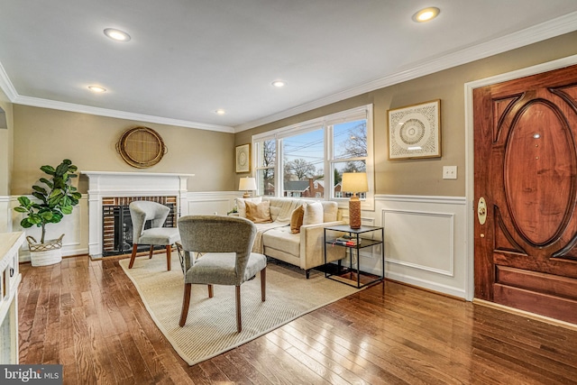 living room with hardwood / wood-style floors, crown molding, and a fireplace