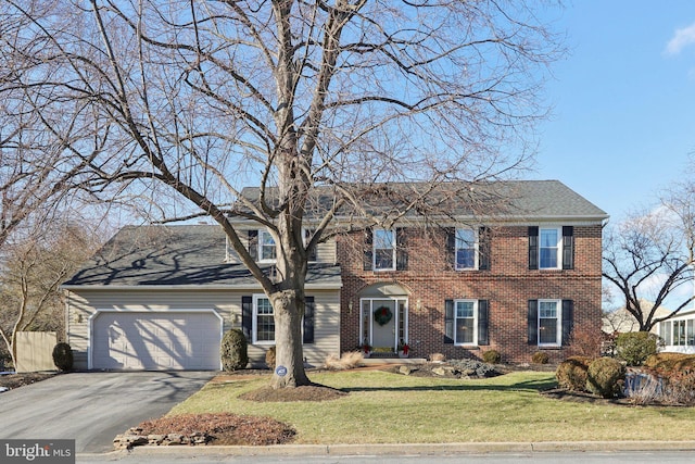 colonial-style house featuring a front yard and a garage