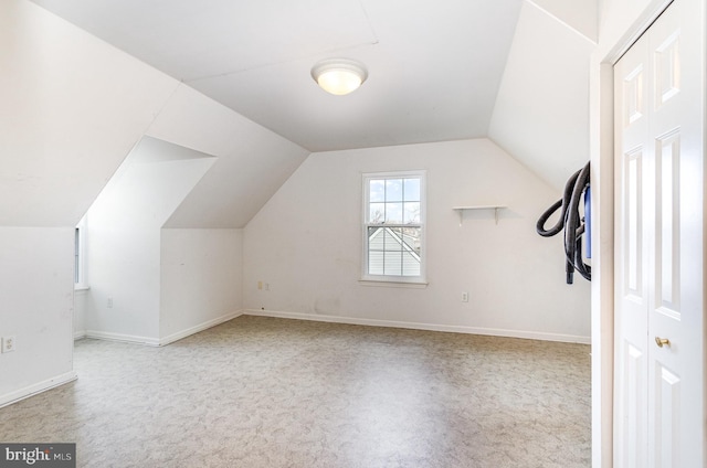 additional living space featuring light colored carpet and vaulted ceiling