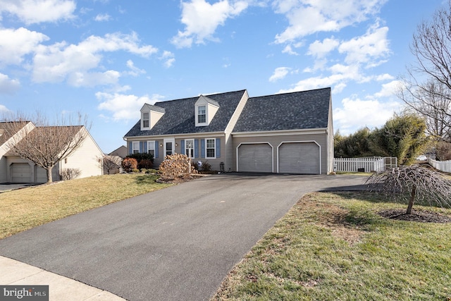 cape cod home featuring a garage and a front lawn