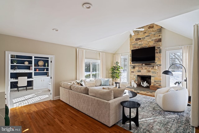 living room with lofted ceiling, hardwood / wood-style floors, built in desk, and a fireplace